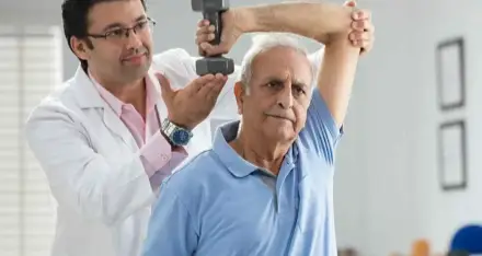 Physiotherapist guiding an older man through an arm exercise