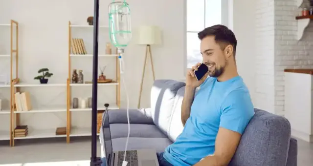 Man relaxing on a sofa during an IV drip at home