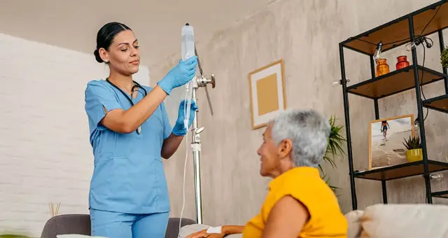 Nurse caring for an older woman on her sofa